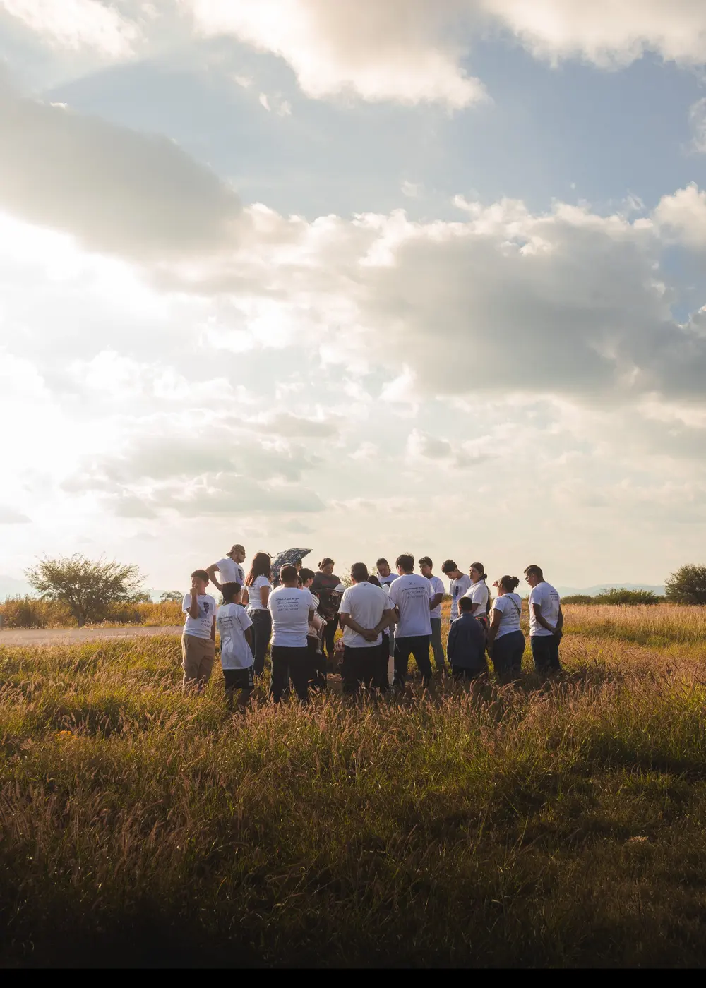 A group gathered in a circle in a field under a wide sky