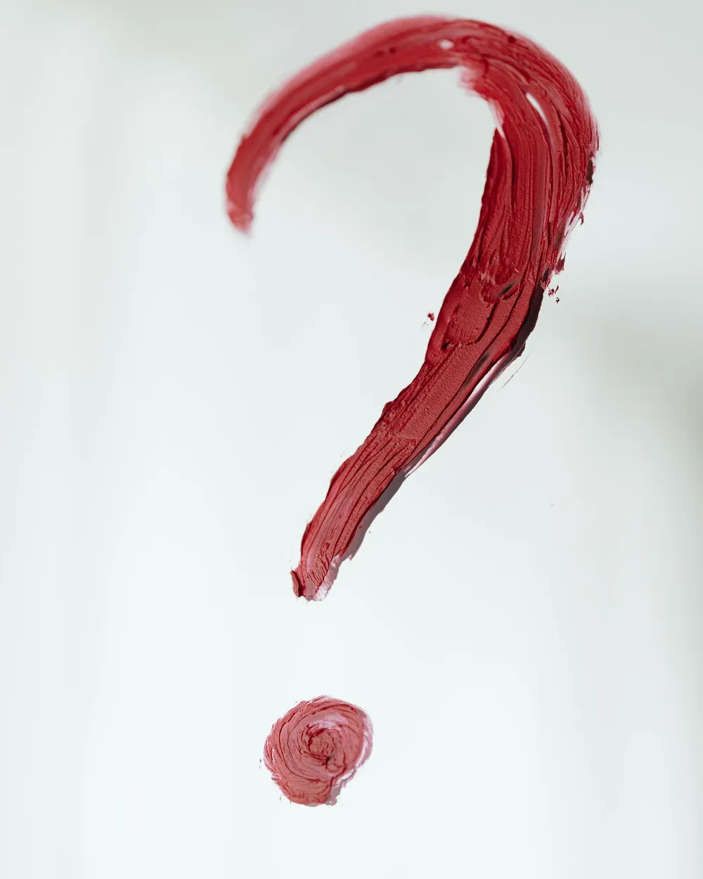 A question mark drawn in red on a light surface